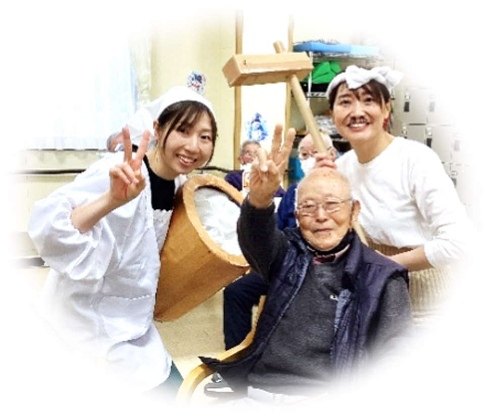 餅つきをした若い女性と利用者が楽しそうに集合しているイメージ